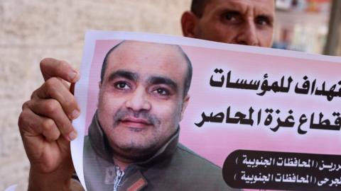 A man holds a picture of Mohammad Halabi, during a solidarity rally outside the office of the International Committee of the Red Cross in Gaza City (30 August 2022)