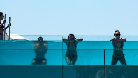 Tourists in Barcelona are seen enjoying a swim in the pool of a hotel as they try and cool off
