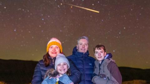 Family with shooting star in background