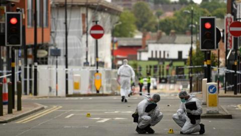 Police forensics officers gather evidence inside a cordon on Hurst Street