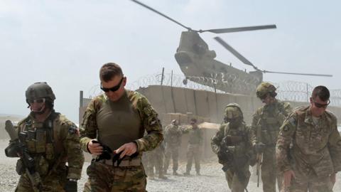 US soldiers walk by as a Nato helicopter flies overhead at a coalition base in the Khogyani district in the eastern Afghan province of Nangarhar. August 12, 2015