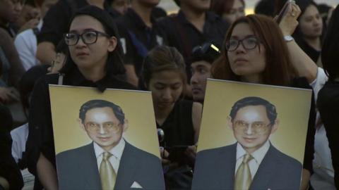 Thai women carry portraits of King Bhumibol Adulyadej