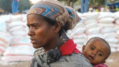 A woman carries an infant in Shire, Tigray region.