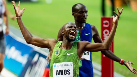 Nijel Amos crosses the line and raises arms in celebration
