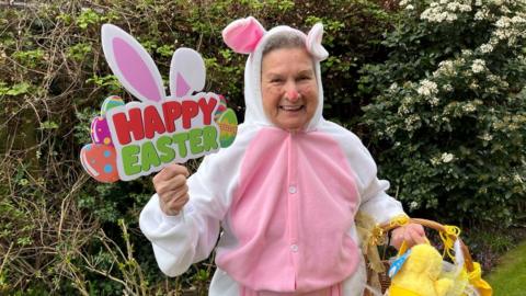 Maria Draper dressed as a bunny and holding a "Happy Easter" sign