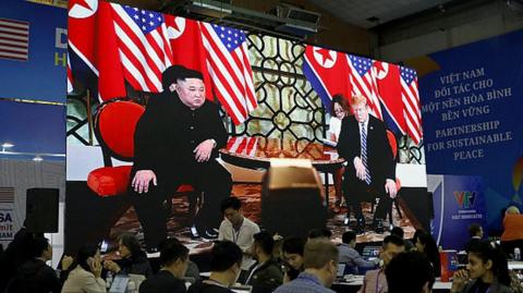 Journalists work next to a large screen displaying news reporting on the second US-North Korea Summit, at the international media centre, in Hanoi, Vietnam, 28 February 2019