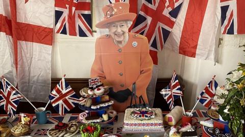 Cutout of the Queen standing in front of a knitted picnic at St Mary's Church in Surlingham
