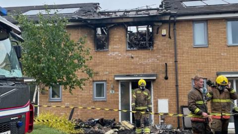 Firefighters outside the damaged house