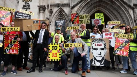 Anti ULEZ protesters stage a demonstration with placards outside the High Court