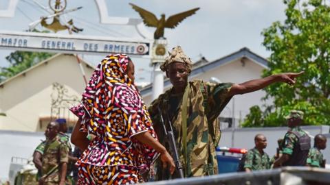 A rebel soldier gestures as he stands near the entrance of the Ivory Coast's army headquarters, the Gallieni military camp, in Abidjan on May 12, 2017 as they fired shots in the air just hours after a spokesman for the protesters publicly apologised for an earlier mutiny