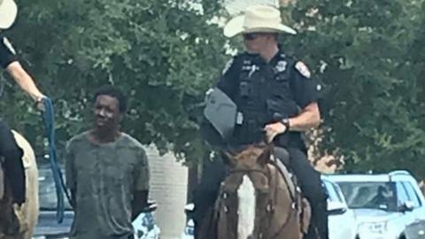 Two officers on horseback leading suspect on foot