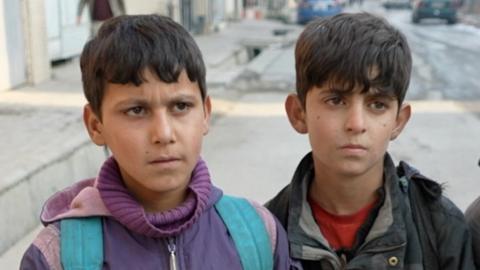 Two Afghan boys walk in the street in Kabul