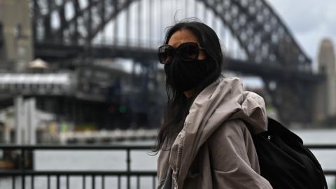 A woman walks past the Sydney Harbour Bridge after stay-at-home orders were lifted across NSW, in Sydney, Australia, Tuesday, October 12, 2021