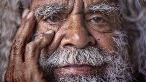 A very close up picture of a white bearded Aboriginal man