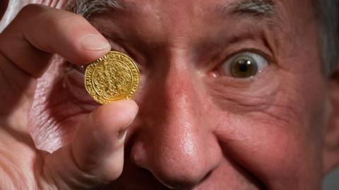 Andy Carter holding up a rare gold coin he discovered that was sold at auction