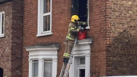 Firefighter on ladder at house window