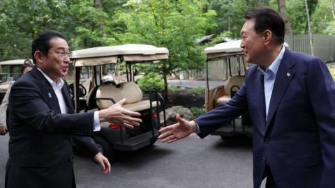 kishida (L) and Yoon shake hands