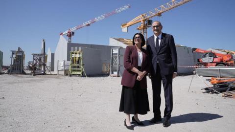 Home Secretary Shabana Mahmood with French Interior Minister, Laurent Nunez, on the site of a new detention centre that is being built in Dunkirk, France. Behind them there are partially constructed buildings and cranes.