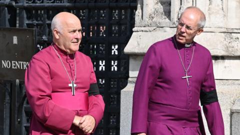 Archbishop of York Stephen Geoffrey Cottrell (left) and The Archbishop of Canterbury Justin Welby outside Westminster Hall, London. They are wearing robes and have a cross hanging around each of their necks.