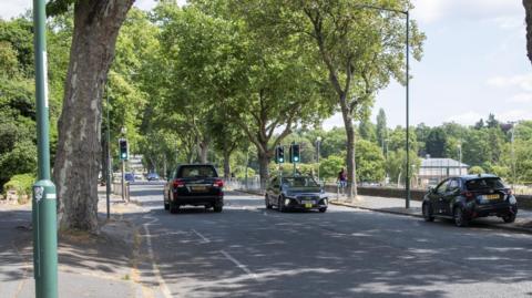 Gregory Boulevard and a tree-lined city street with cars and a pedestrian in view.