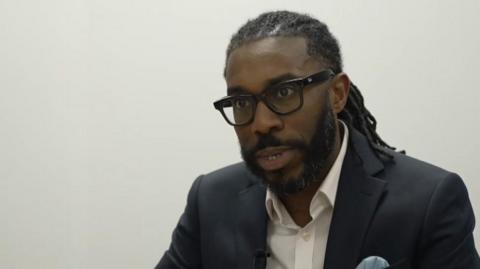 Teacher Marlon James-Edward, wearing glasses and speaking