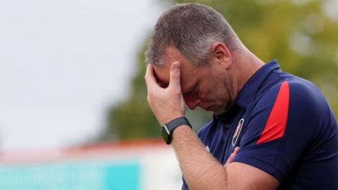 Michael Flynn holds his head in his hands on the touchline