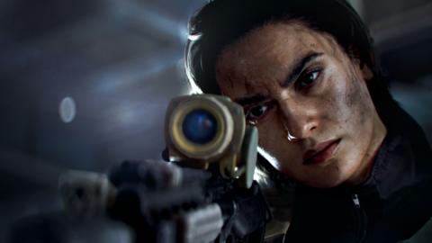 Screenshot from Battlefield 6 shows a female sniper resting her cheek on the stock of a long-range rifle as she looks down its scope. There is a look of concentration on her face, which is flecked with black dust.
