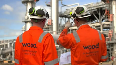 Two Wood Group workers wearing bright orange jackets and white helmets