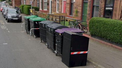 A line of communal bins on a residential street.