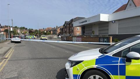 Police tape blocking the road near a supermarket