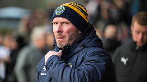 Shrewsbury Town boss Michael Appleton in warm coat and club beanie hat