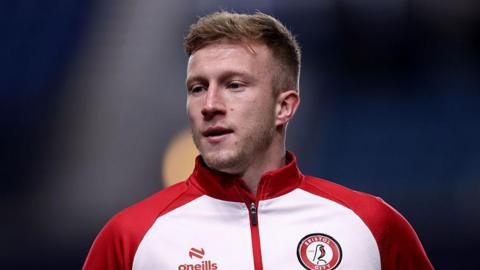 Ross McCrorie wearing a red and white Bristol City training jacket, looking towards his right 