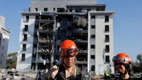 Israeli soldiers work next to a damaged residential building at an impact site following Iran's missile strike on Israe