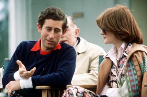 Prince Charles, Prince of Wales, wearing a navy blue Ralph Lauren jumper, sits next to his girlfriend and sister of Lady Diana Spencer, Lady Sarah Spencer