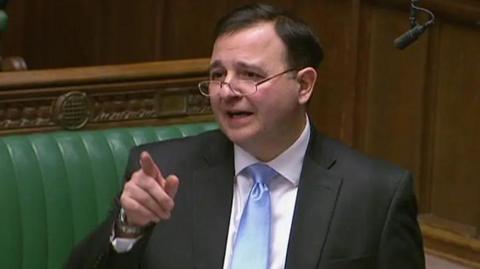 Alberto Costa making a point in the House of Commons, against backrop of green benches