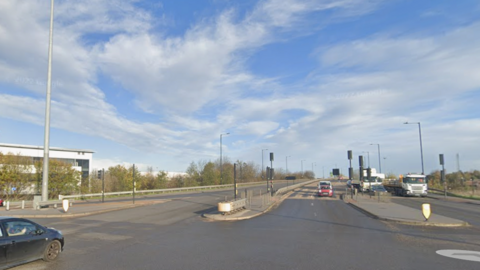 A big road, with a few cars driving on it in the distance 
