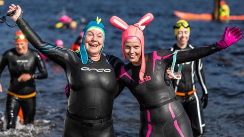 Two swimmers, one with bunny ears, in wet suits after completing the Kessock Ferry Swim