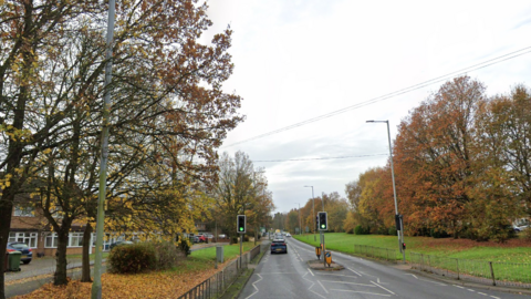Cannock Road going out of the city. Trees are on both sides of the road with houses on the left.