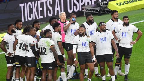 Group of Fiji players in black and white kit on the field in 2024