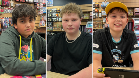 A composite image of three boys smiling at the camera. They are sitting at the same table within a games cafe. The boy on the left has brown hair and wears a green hoodie. The boy in the middle has blond curly hair and is wearing a black T-shirt with a chain on. The boy on the right wears a yellow cap and a black T-shirt.
