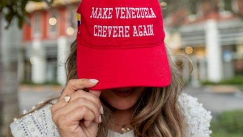 A resident shows a Maga-style red baseball cap with the words "MAKE VENEZUELA CHEVERE [great] AGAIN" during celebrations in a Venezuelan enclave in Miami, following the raid and removal of Maduro and his wife
