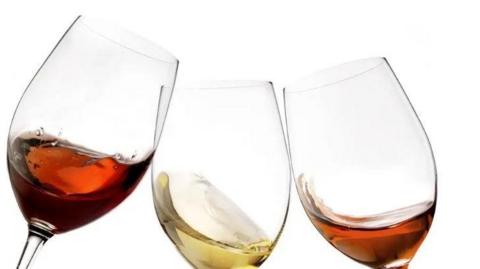 Three glasses with wine in them, against a white background