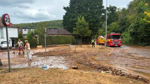 A fire engine can be seen at a street, which is covered in mud and stones. 