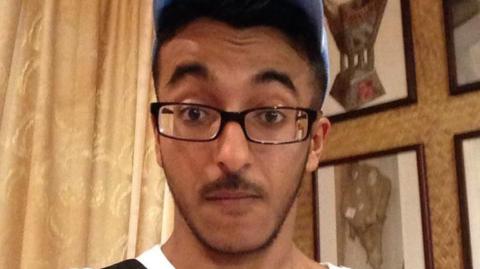 Mazin Kaladi looks at the camera. He has dark facial hair and is wearing a blue baseball cap and dark glasses.