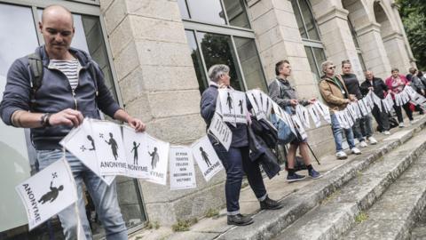 People holding a long banner made of sheets of paper
