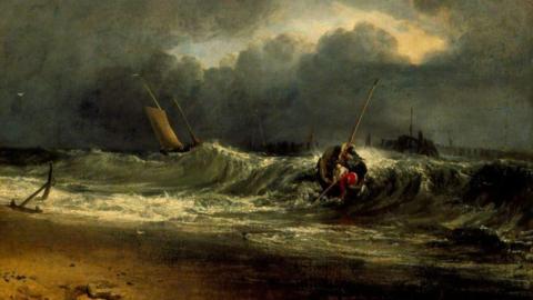 Dark stomy sky with large waves crashing onto a beach - several fishing boats are seen on the crashing waves a gap of light in the clouds is centred over the sea.