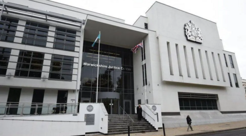 The front of a large white building with black framed windows and doors and steps leading up to a large entrance