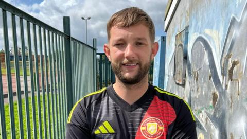 Joel Collins, who was attacked after a football game, smiles at the camera in his football kit