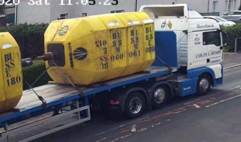 A blue and white lorry with two large yellow buoys mounted on the back