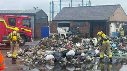 Firefighters monitoring a pile of waste at the depot